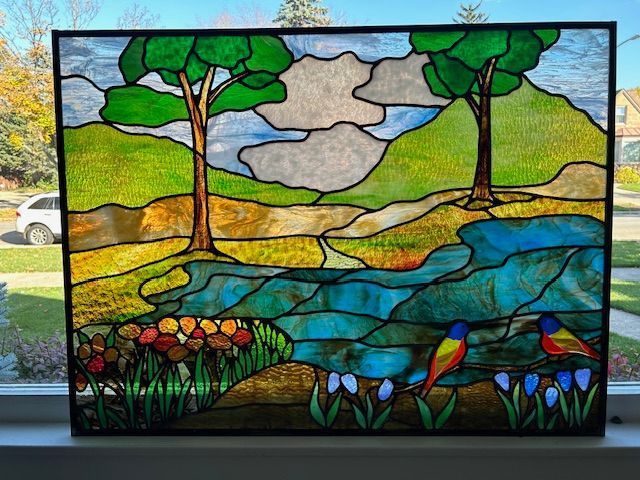 A stained glass painting of a landscape with trees and birds
