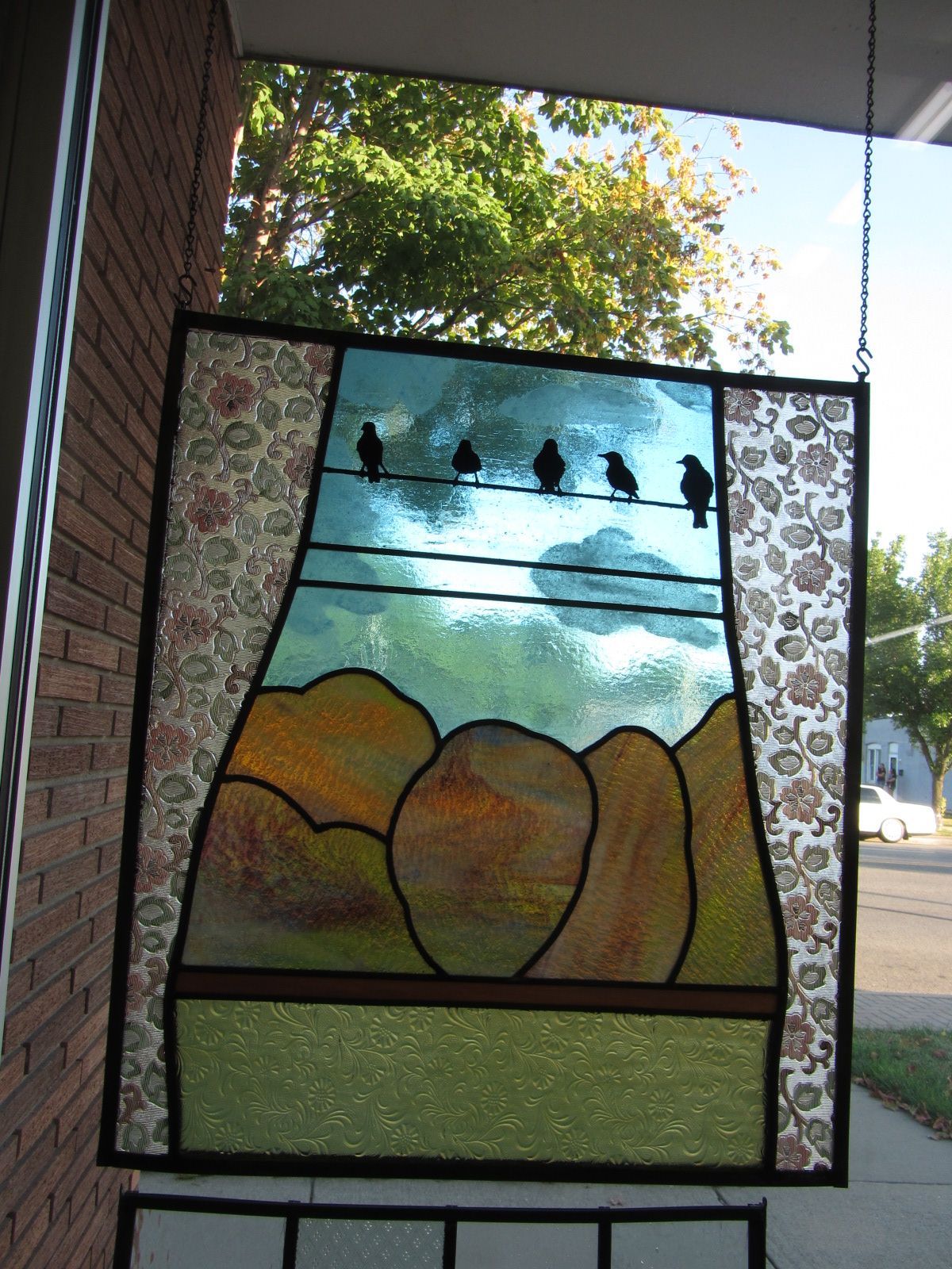 A stained glass window with birds on a wire