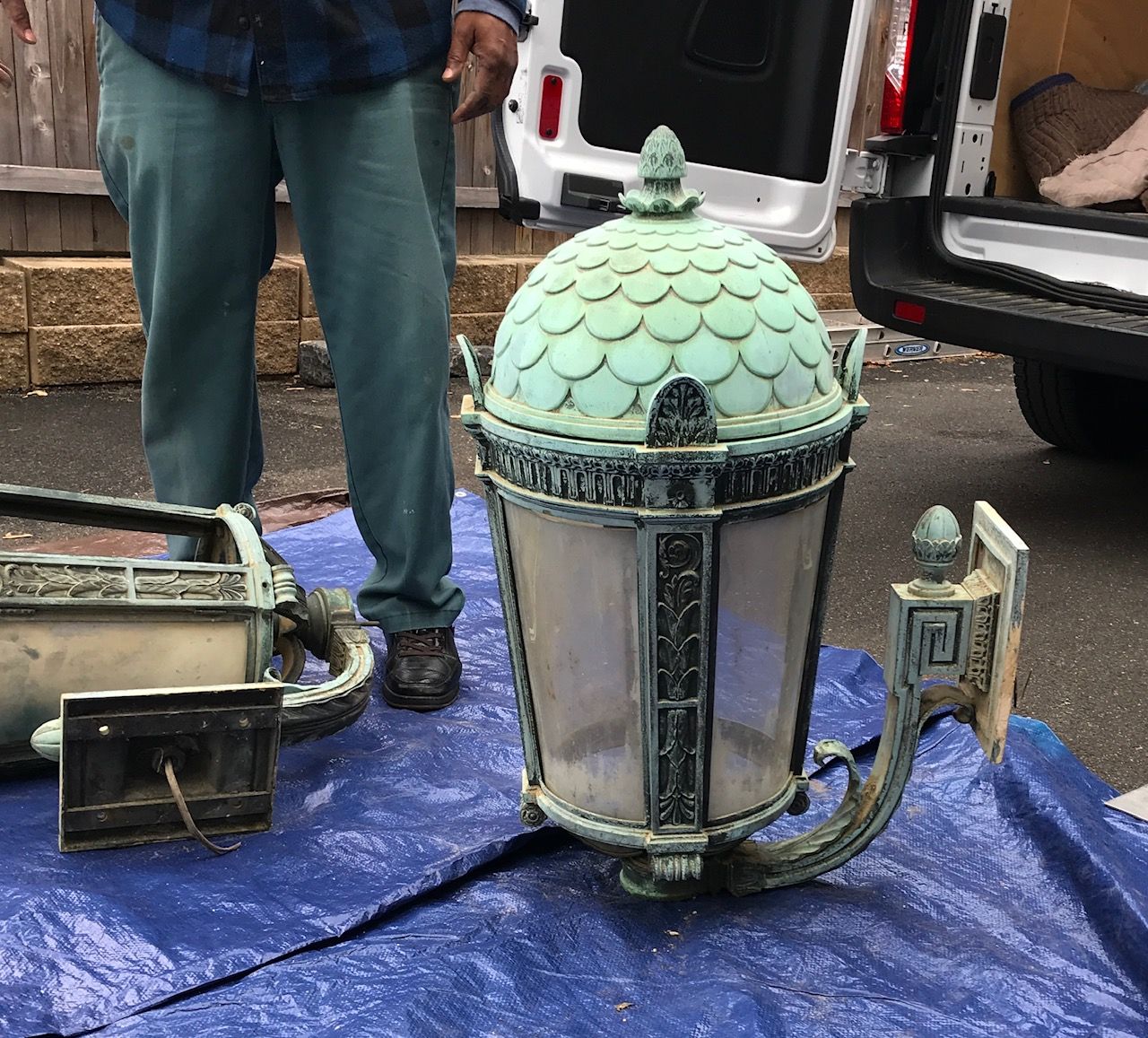 A man is standing next to a lantern on a blue tarp