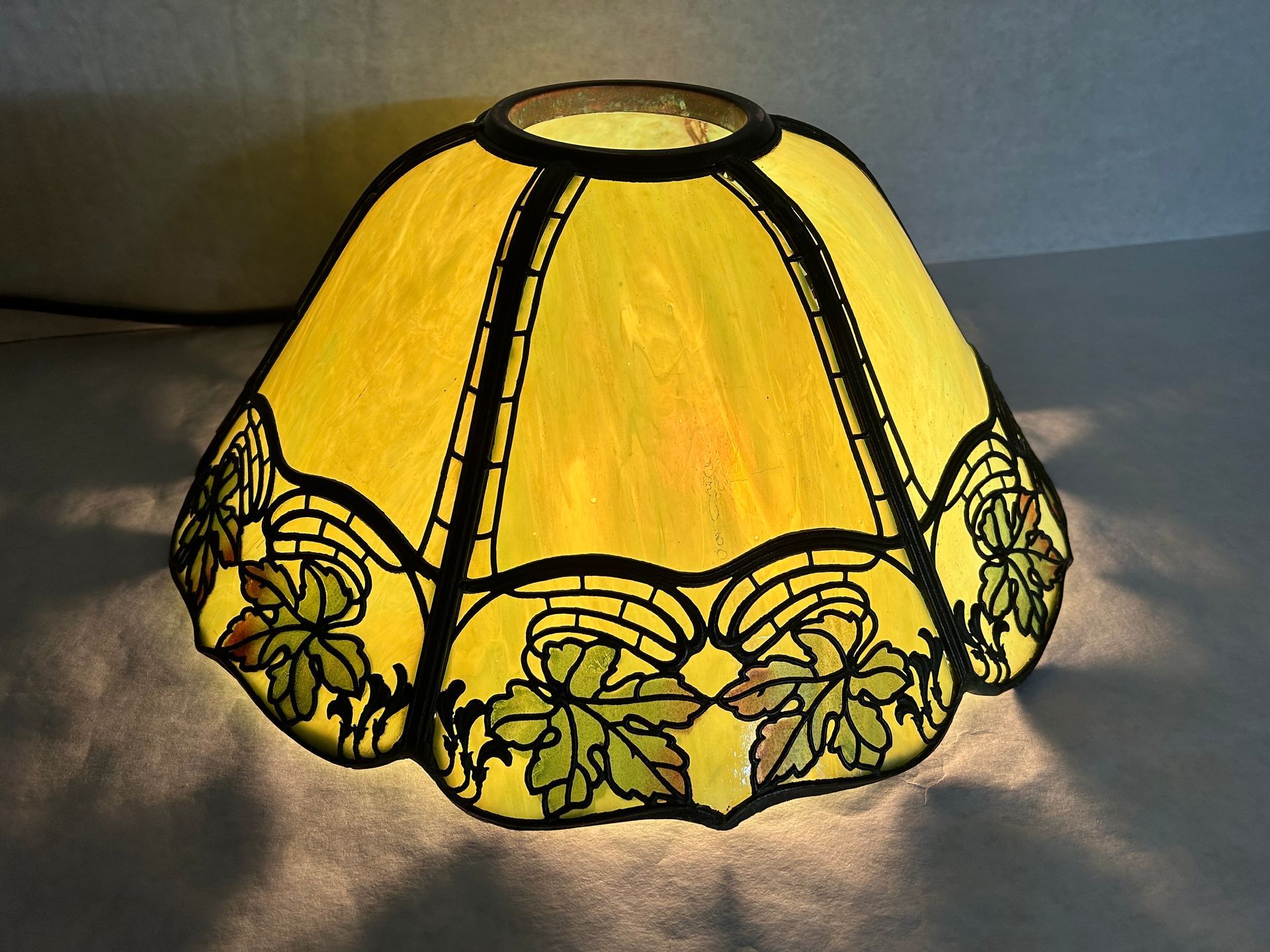 A yellow lamp shade with leaves on it
