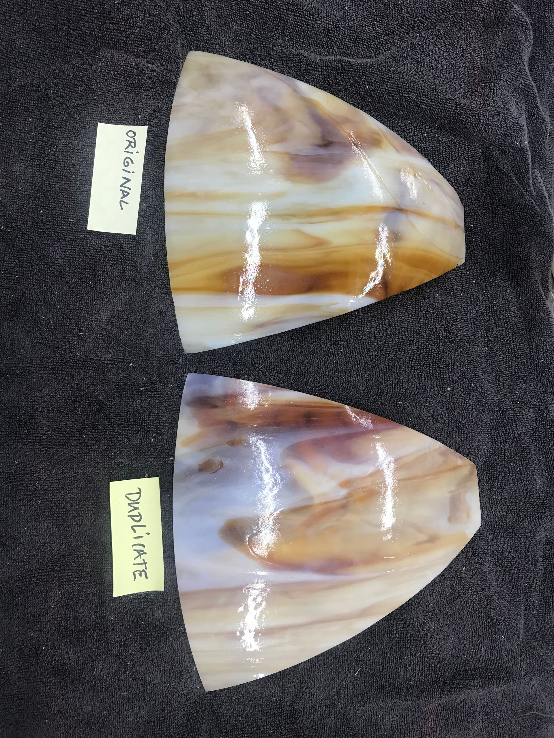 Two pieces of glass are sitting next to each other on a black surface.