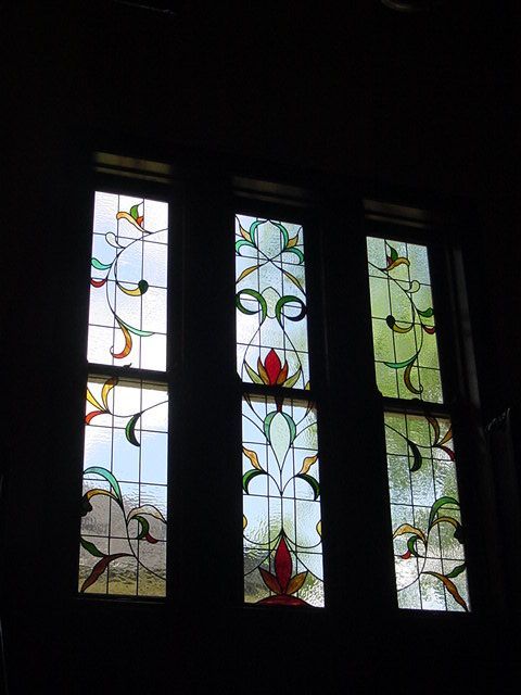 A stained glass window with a floral design in a dark room.