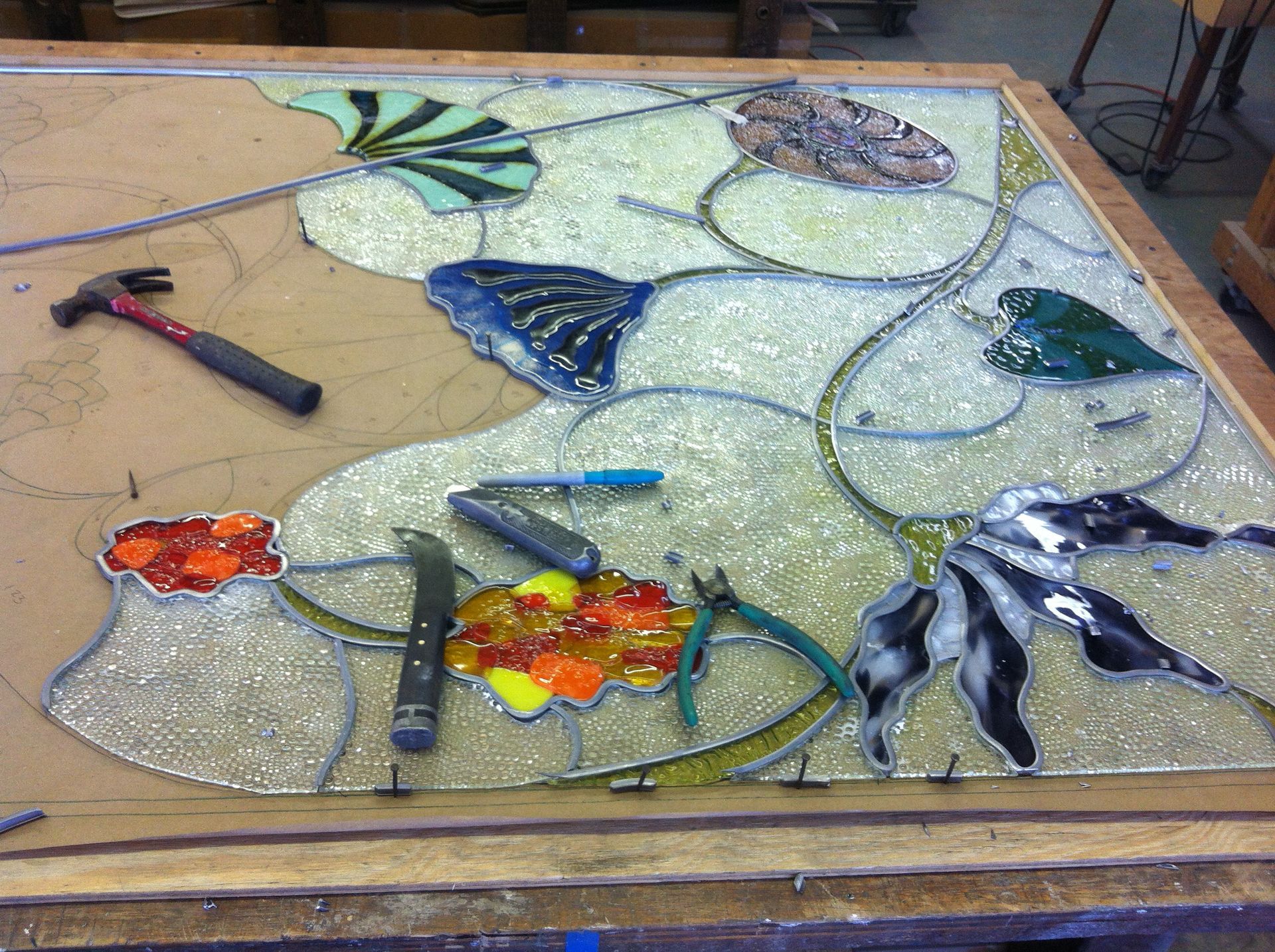 A piece of stained glass is being worked on on a table