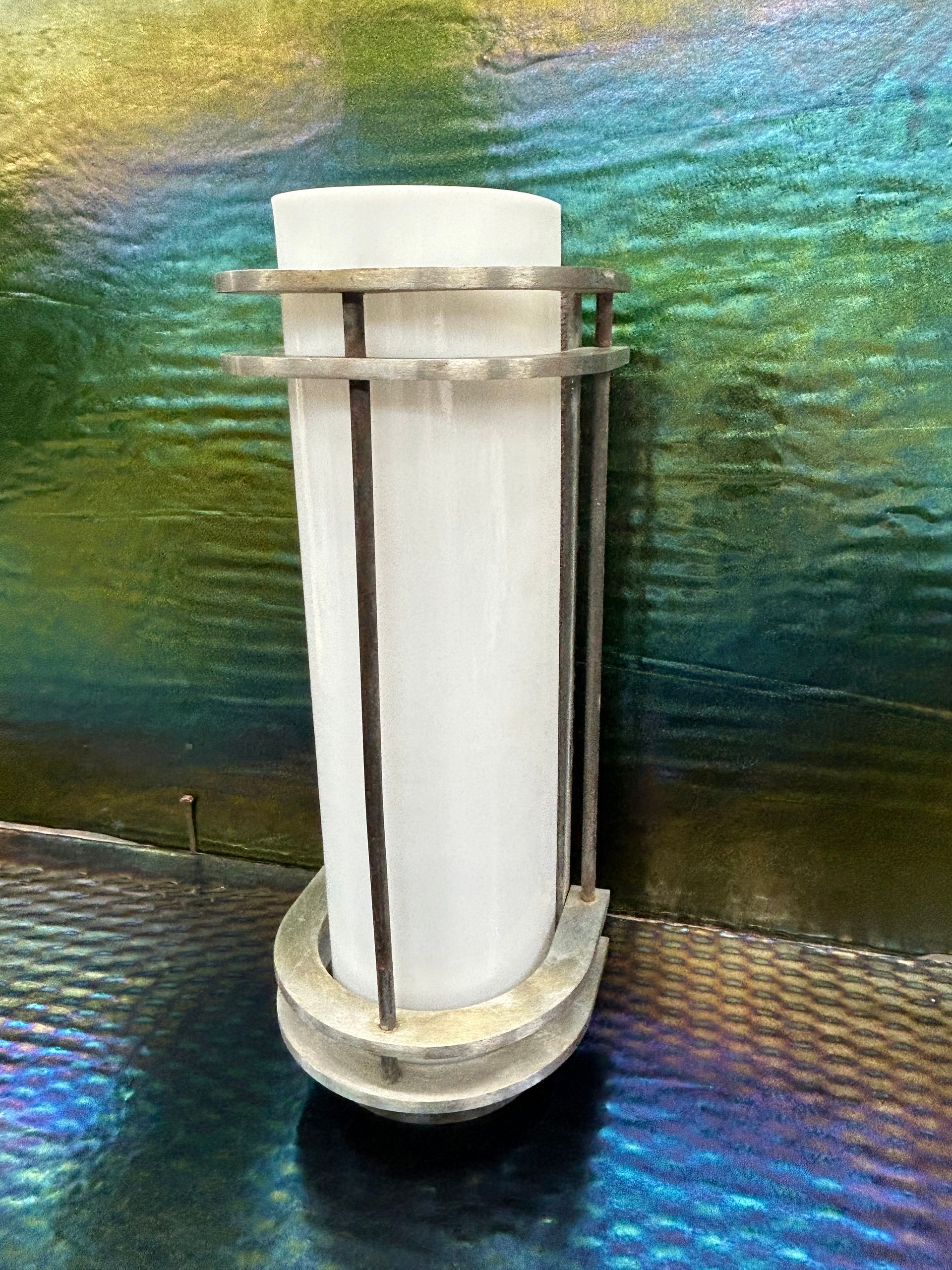 A candle holder is sitting on a table in front of a colorful wall.