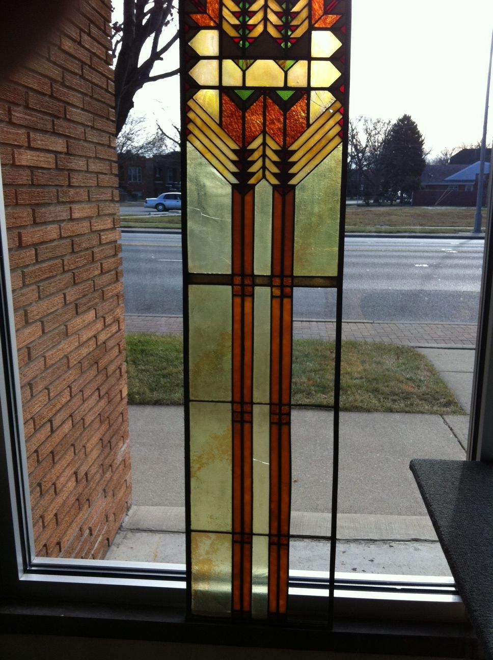 A stained glass window with a brick wall in the background