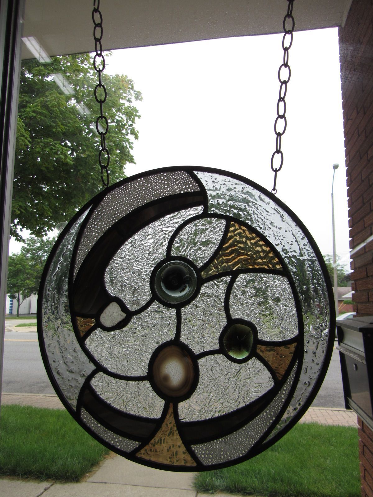 A stained glass window hanging from chains outside