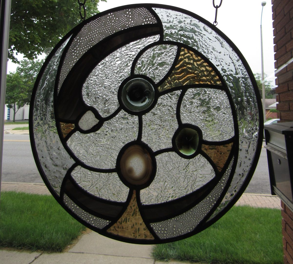 A stained glass window hanging from chains outside