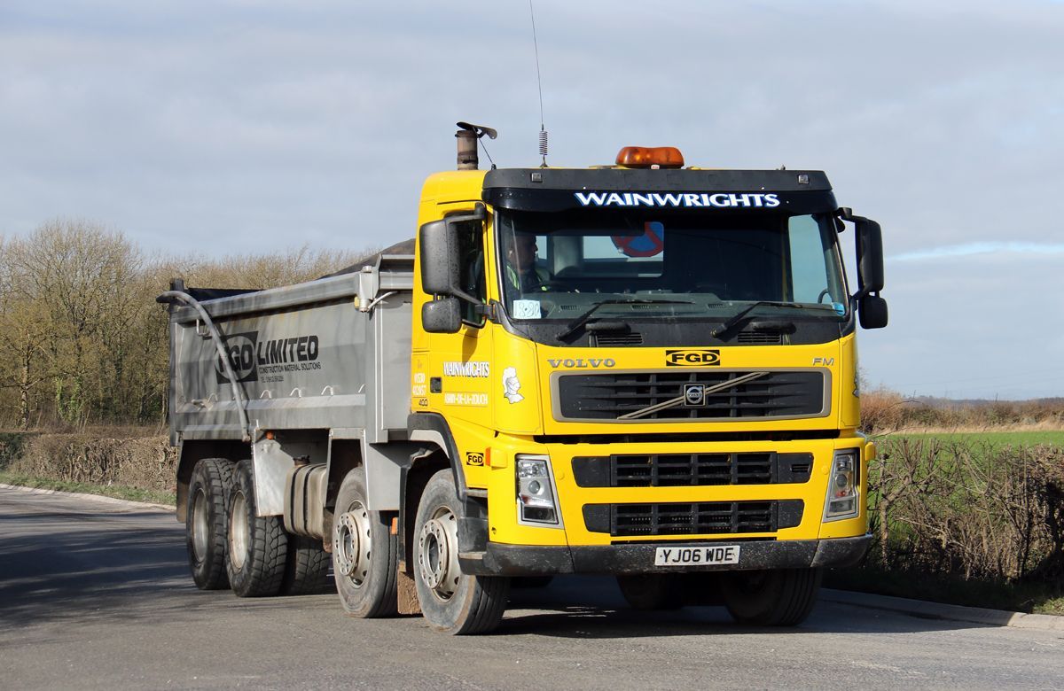 Yellow Volvo dump truck on a rural road; cab and dump bed visible; overcast sky. Wainwrights