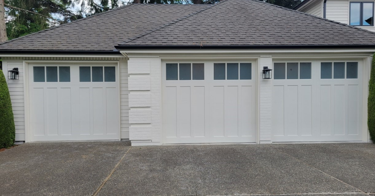 Carriage house garage doors in white and wood tones on a three door garage displayed by Garage Tech of Bothell Washington