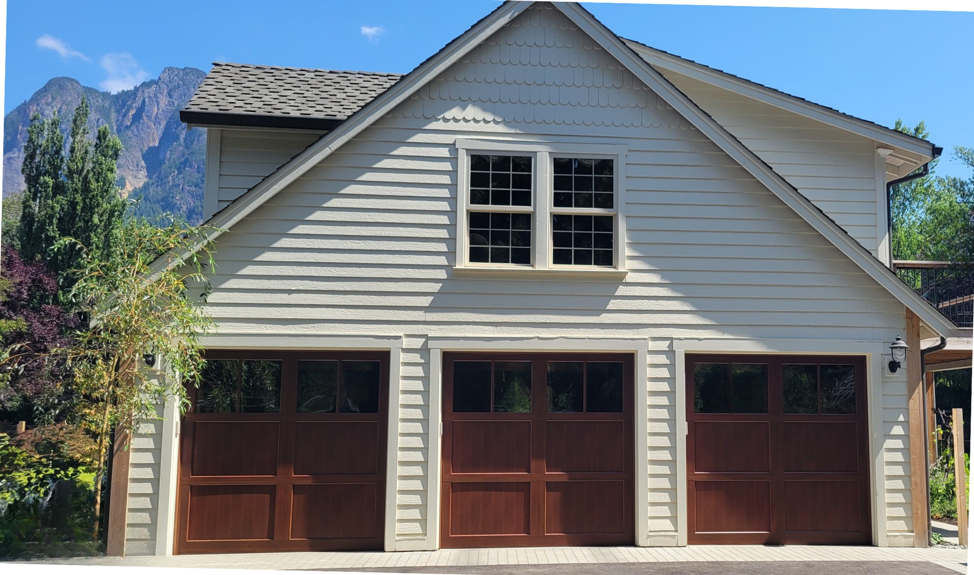 Natural wood stained carriage house garage doors on a three door garage displayed by Garage Tech of Bothell Washington