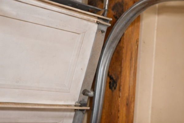 Garage door off track with rollers detached and door tilted unevenly