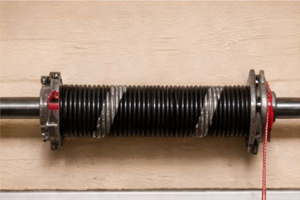 Newly installed torsion spring mounted above a residential garage door after professional spring replacement