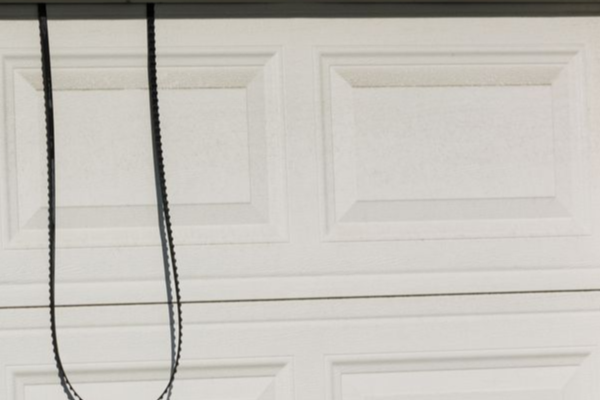 Garage door lift cable draped over door panel after snapping from tension