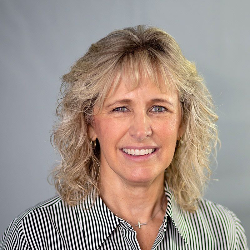 A man in a suit shakes hands with another man in a blue shirt