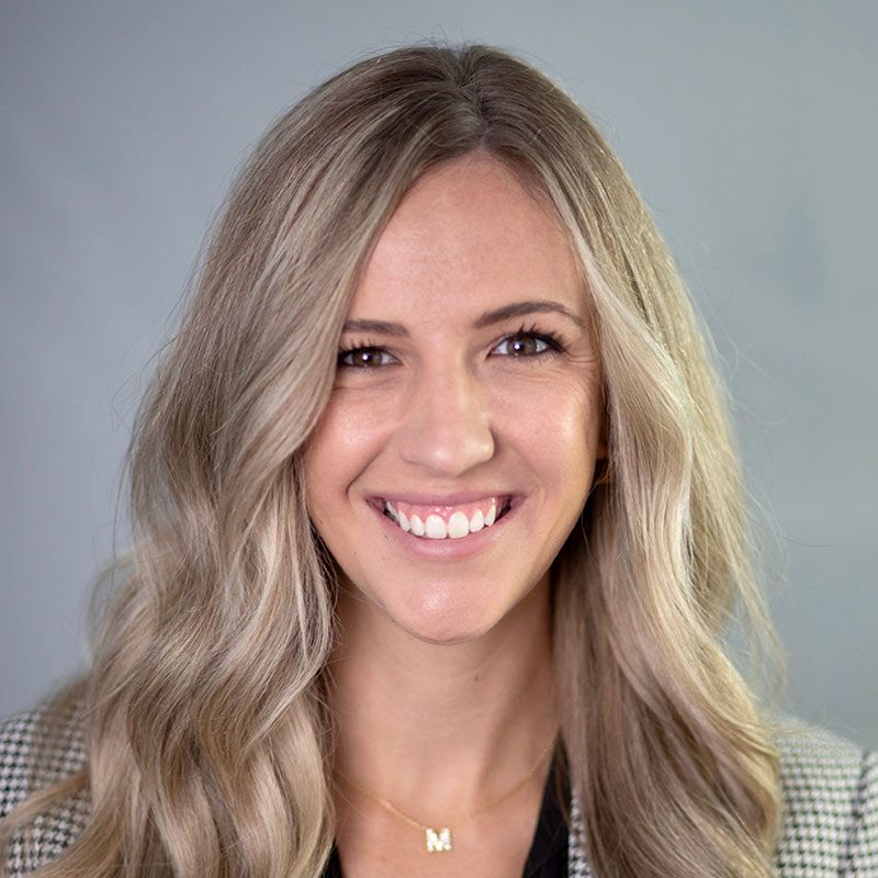 A man in a suit shakes hands with another man in a blue shirt