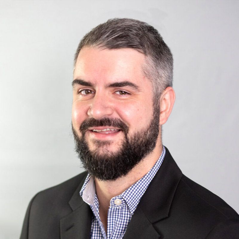 A man in a suit shakes hands with another man in a blue shirt