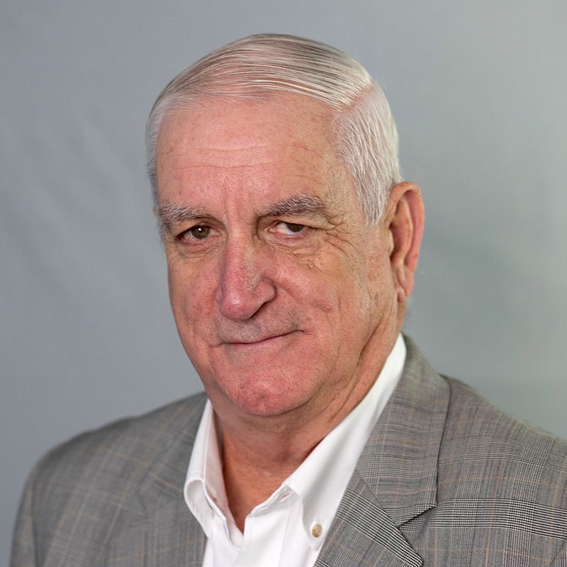 A man in a suit shakes hands with another man in a blue shirt