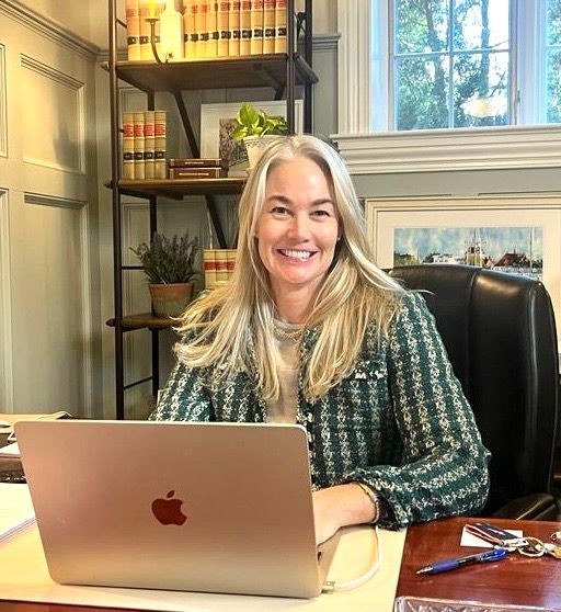 a woman is sitting at a desk with an apple laptop .