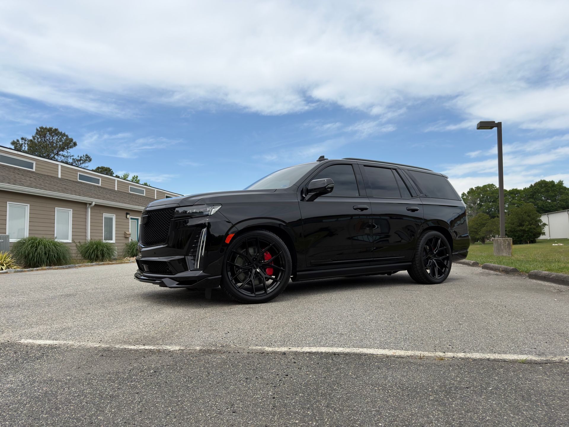 Black SUV with red brake calipers parked outside a brick building under a cloudy sky