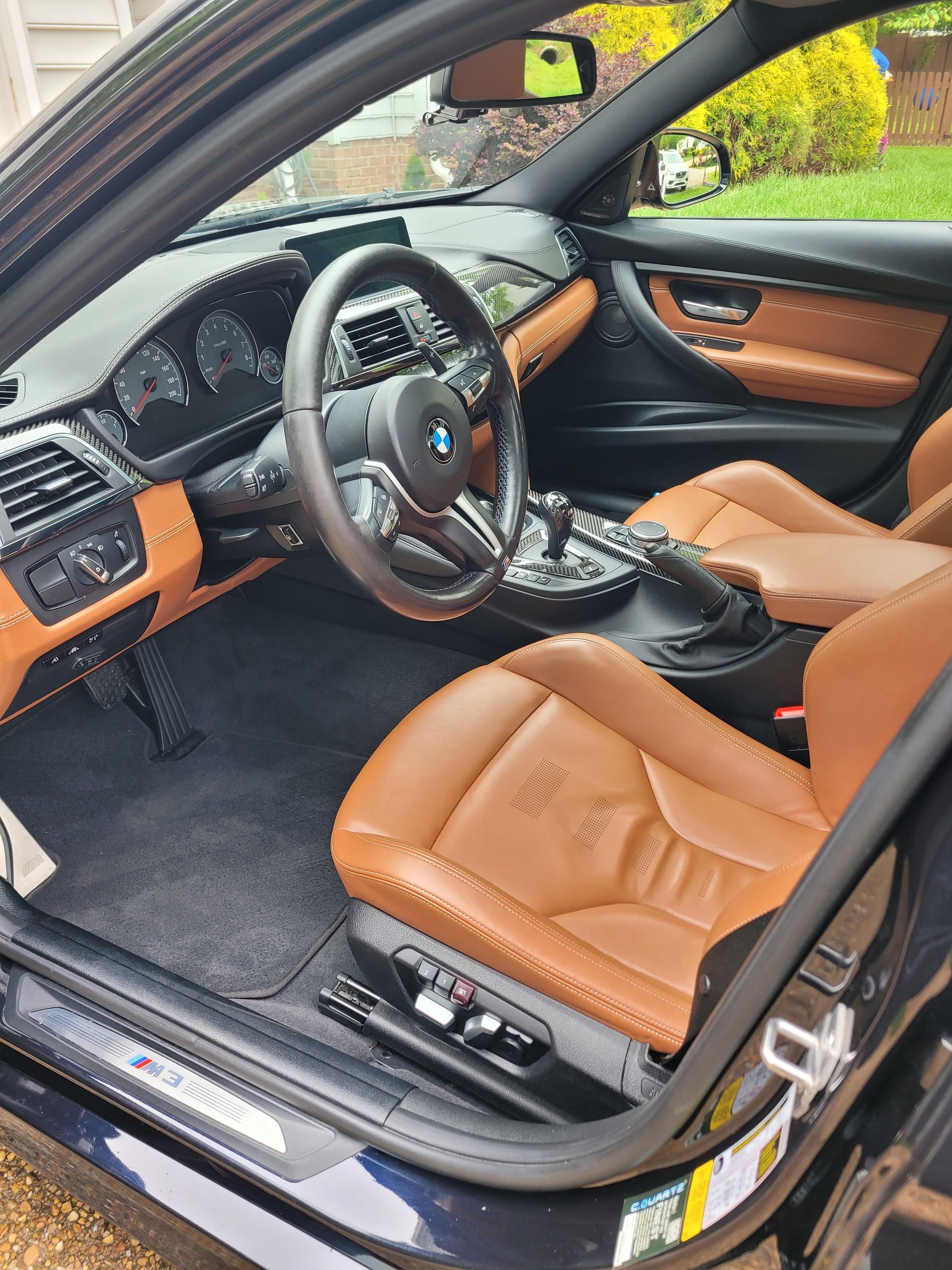 The interior of a black car with brown leather seats and a steering wheel.