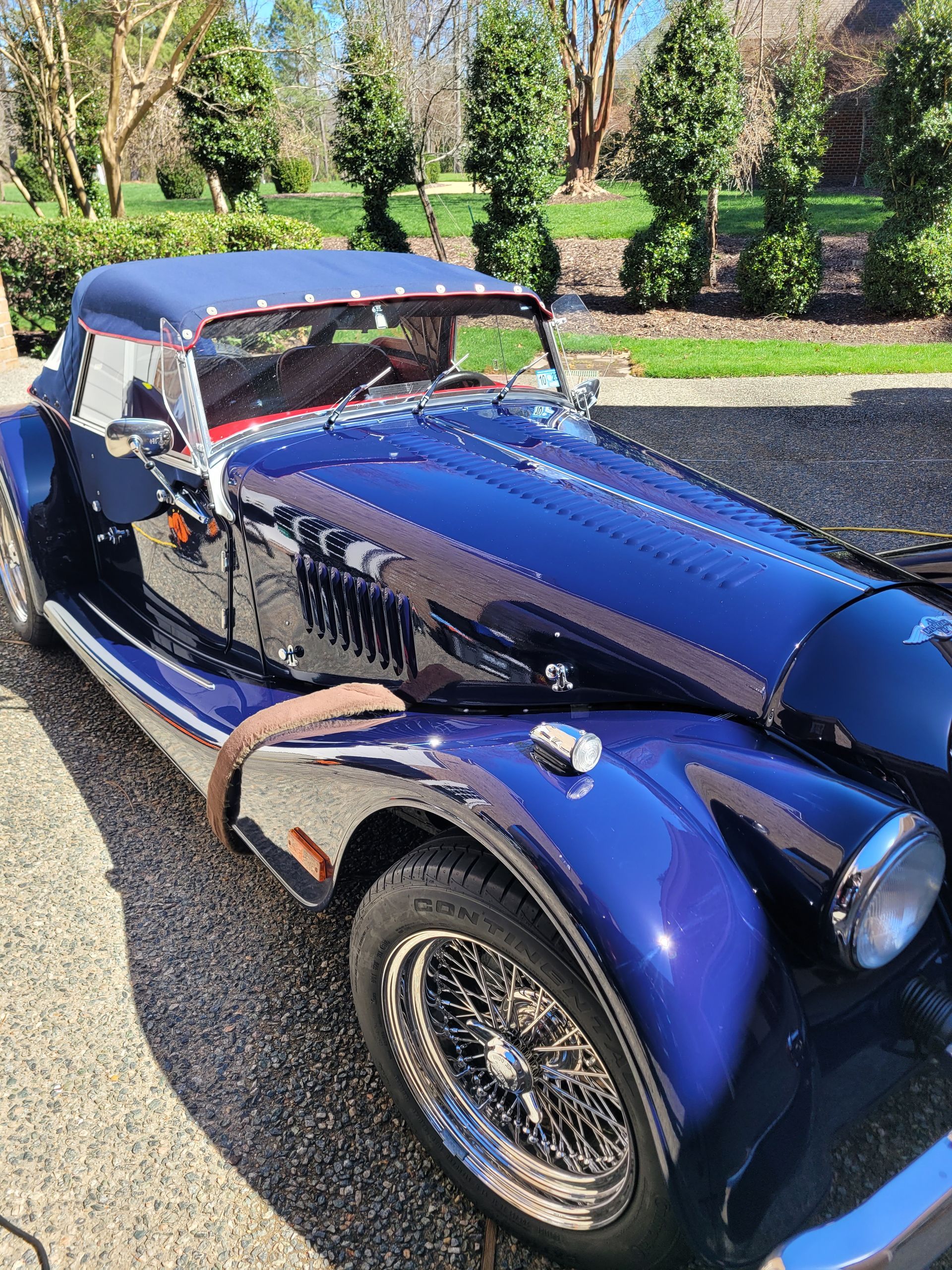 A blue vintage car is parked in a driveway.