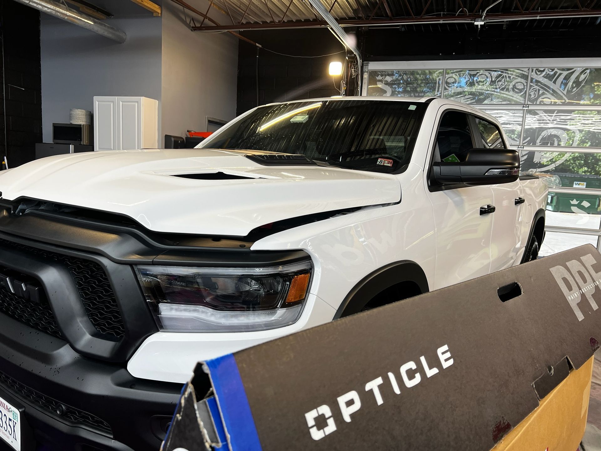 A white truck is parked in a garage next to a box.
