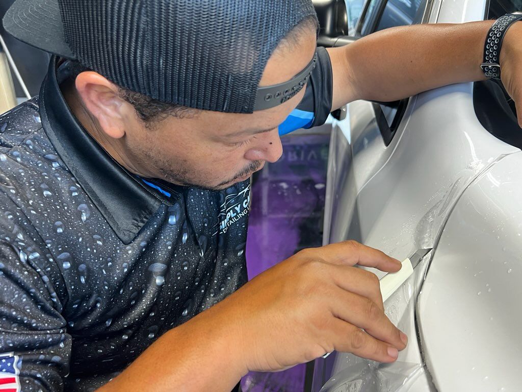 A man wearing a hat is working on a car.