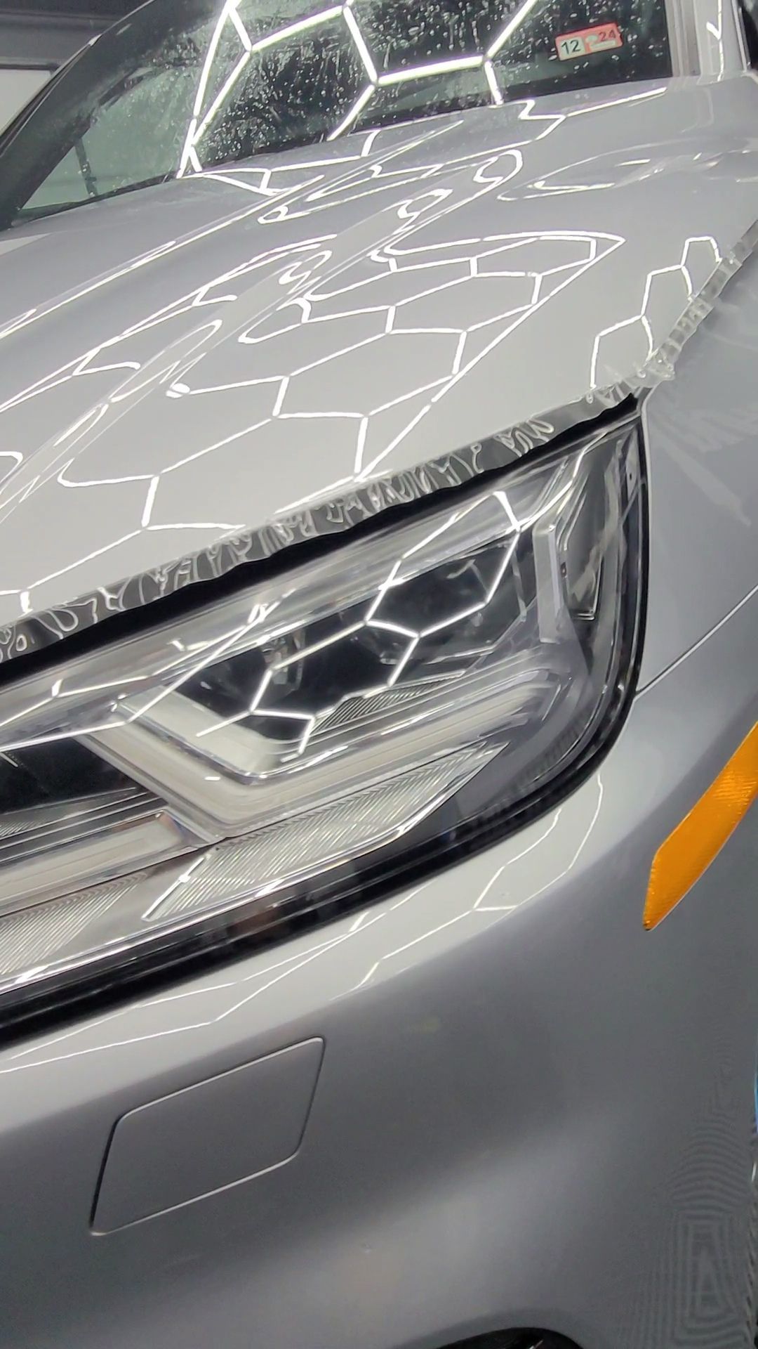 A close up of a car 's headlight and hood.
