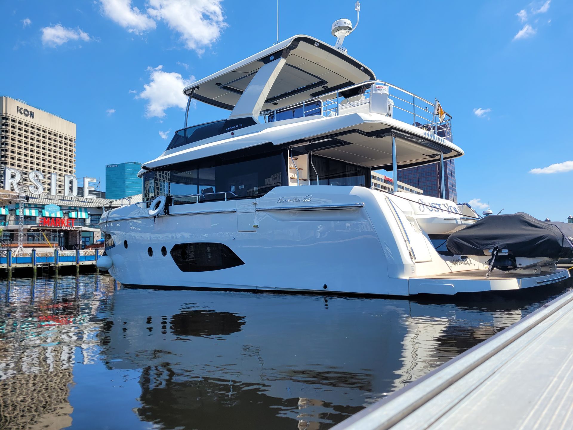 A large white yacht is docked at a marina.
