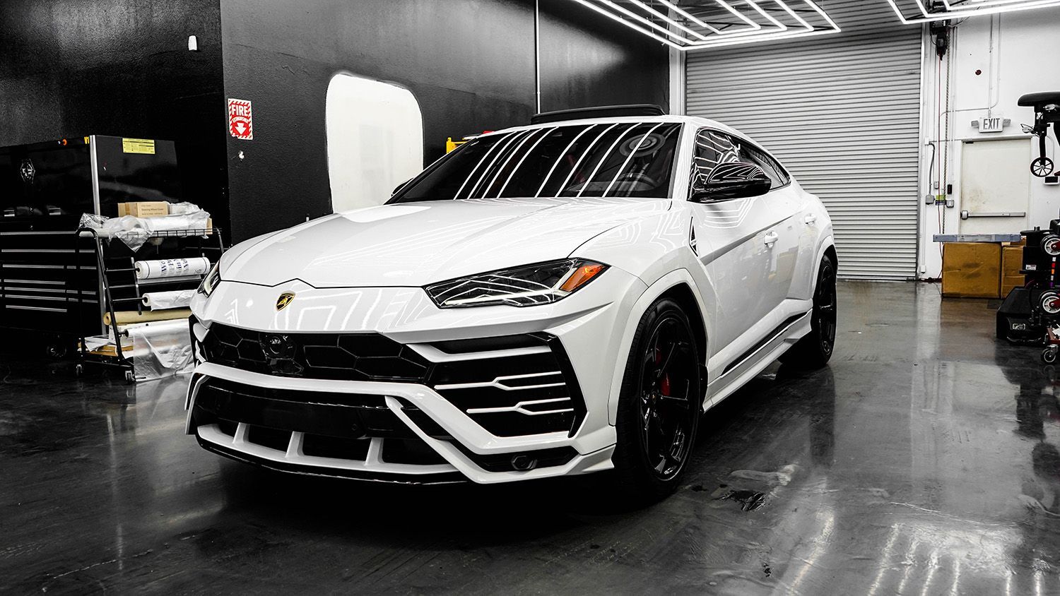 A white lamborghini urus is parked in a garage.