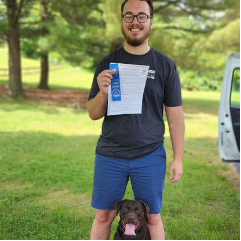 A man is standing next to a dog and holding a ribbon.