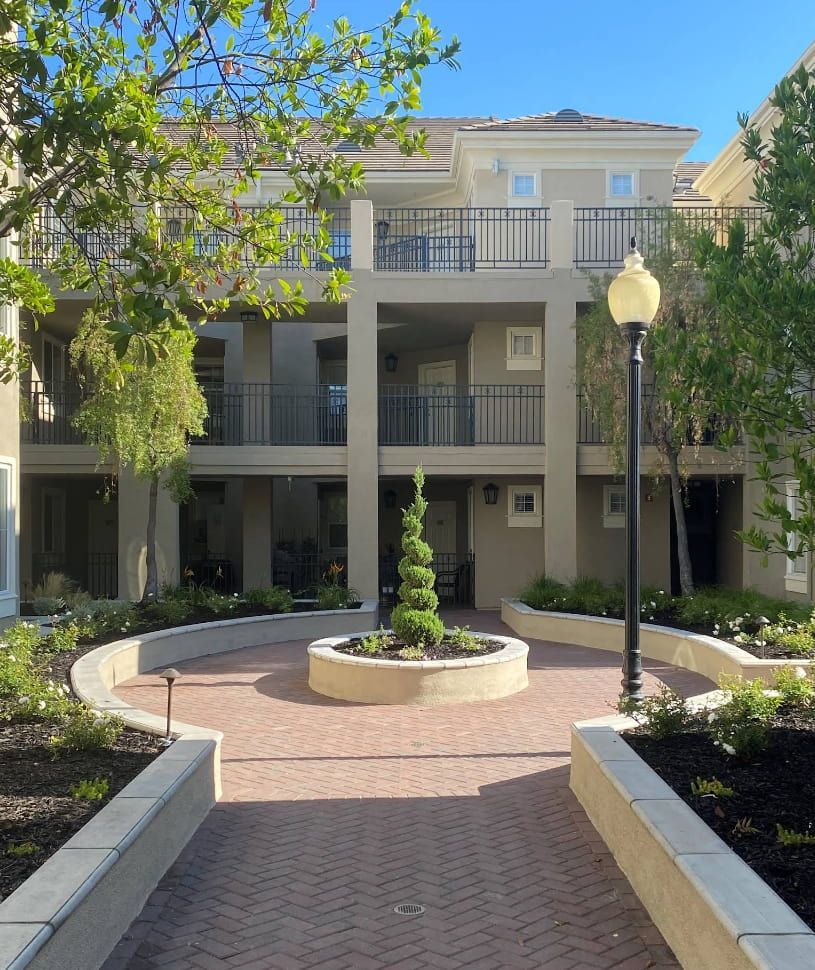 Courtyard with beige apartment building, brick path, and central plant bed.