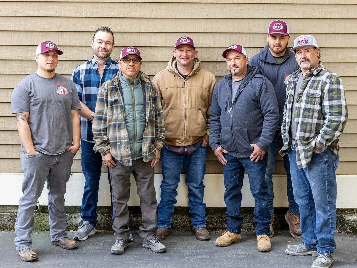 Group of men in work attire and hats posing outdoors.