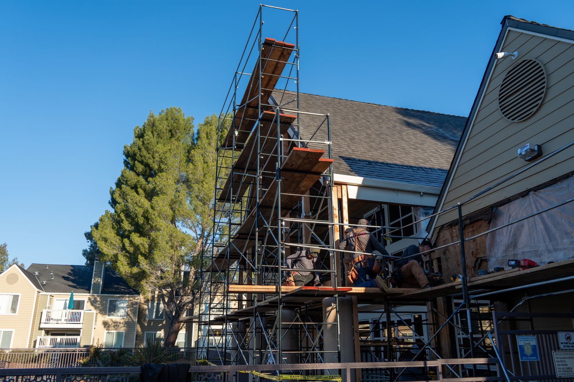 Exterior of a stucco apartment building with balconies, gray siding, and a clear blue sky.