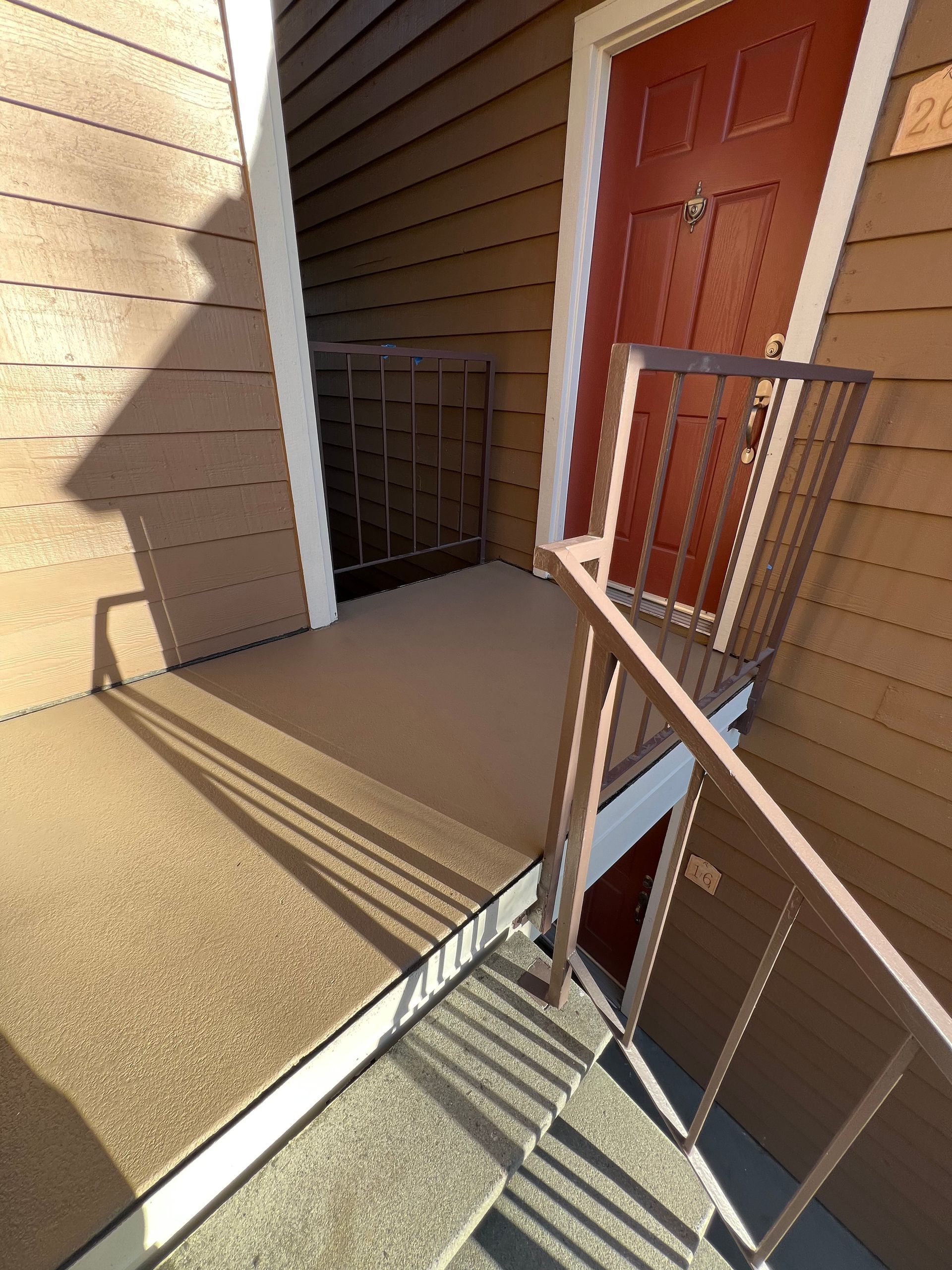 A partially constructed wooden deck on a house with white railing.