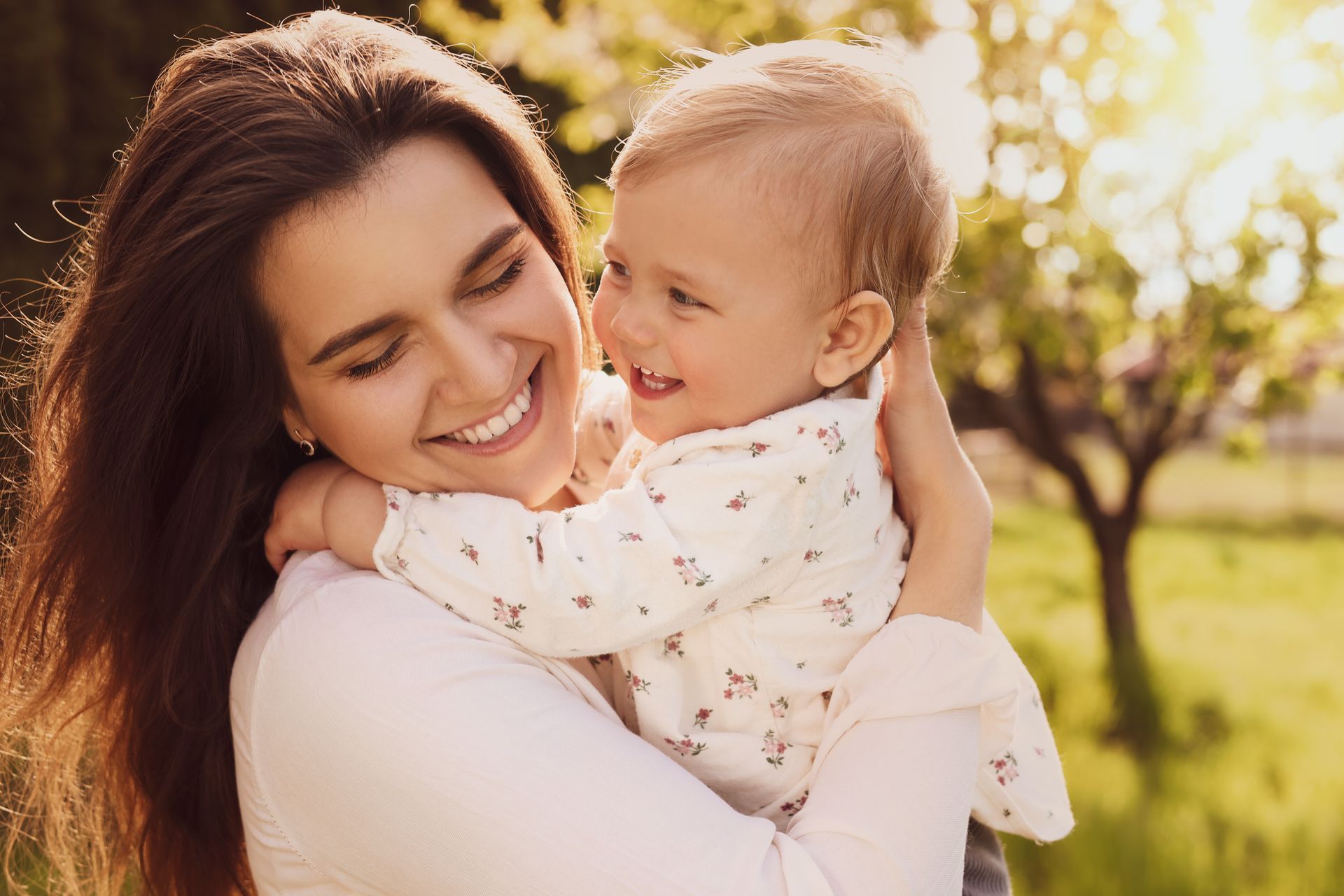 A woman is holding a baby in her arms and smiling.