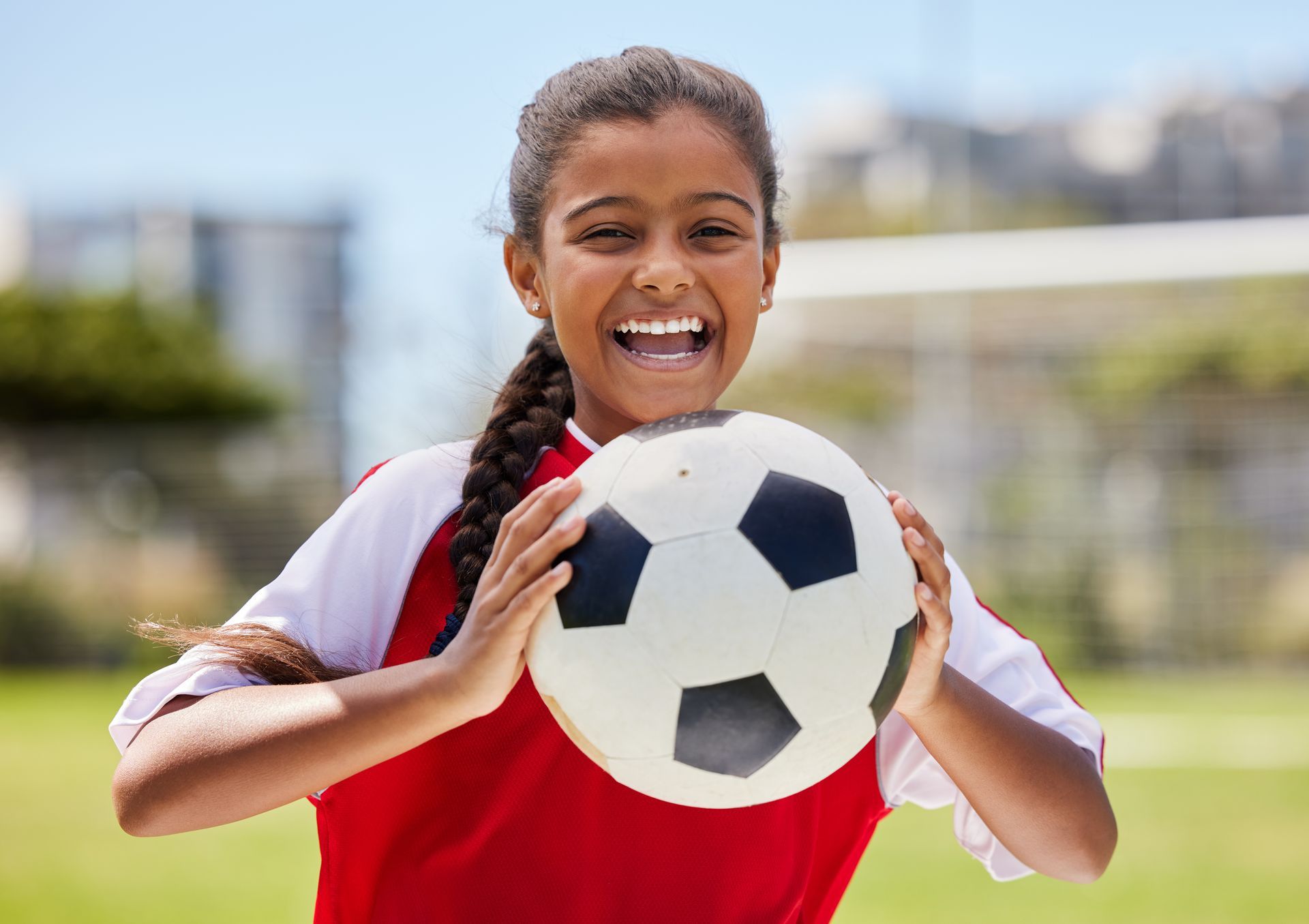 A young girl is holding a soccer ball in her hands on a field.