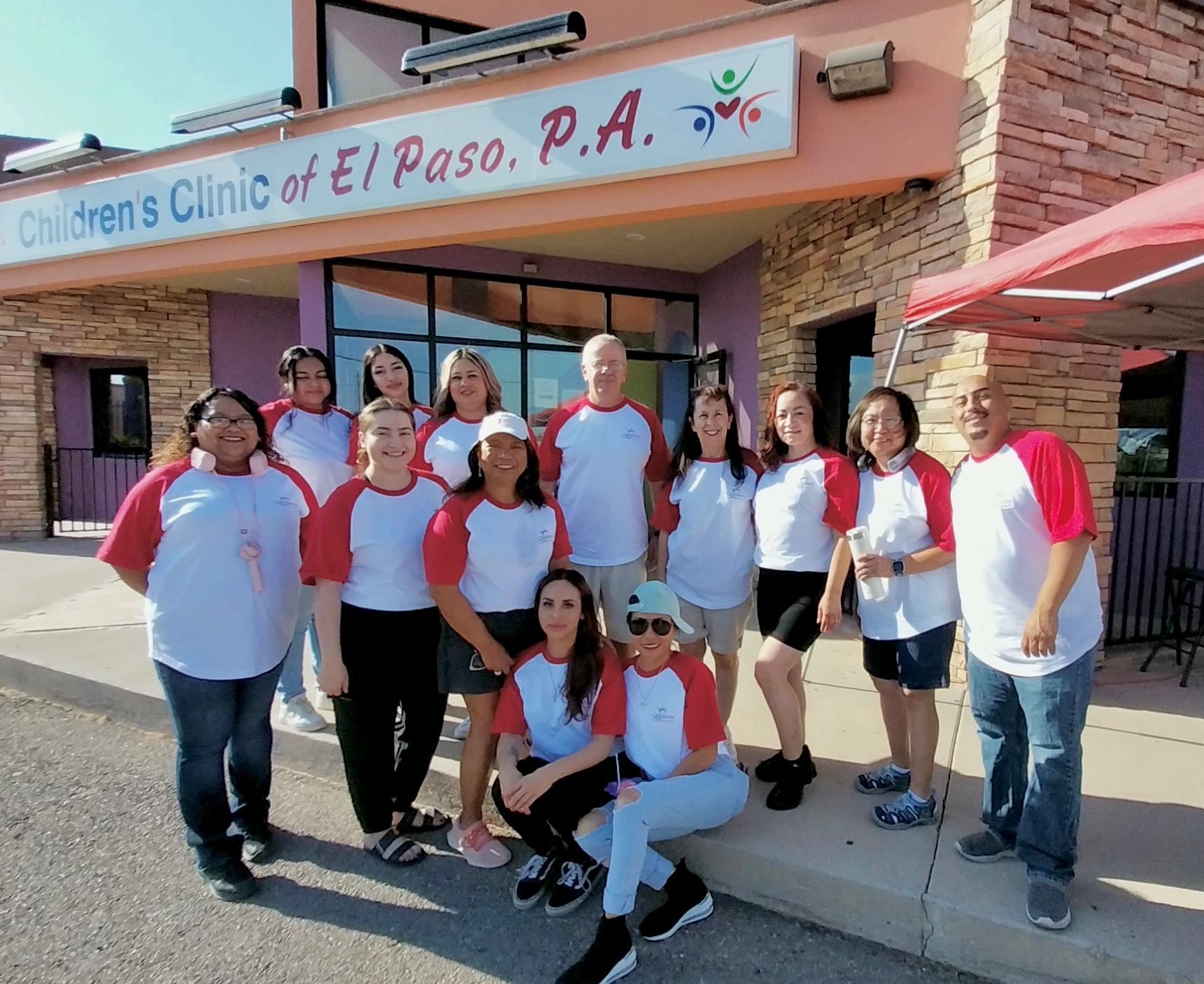 A group of people posing for a picture in front of the children 's clinic of el paso p.a.