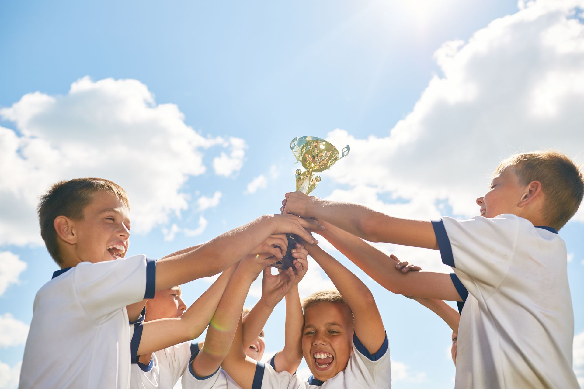 A group of children are holding a trophy in their hands.