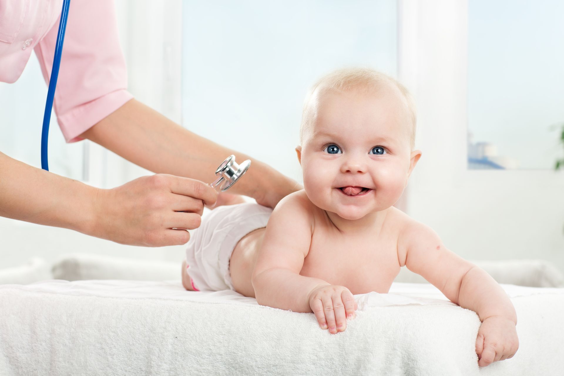 A baby is being examined by a doctor with a stethoscope.