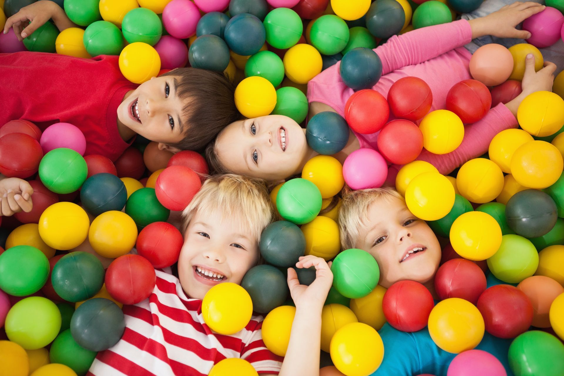 A group of children are laying in a ball pit.