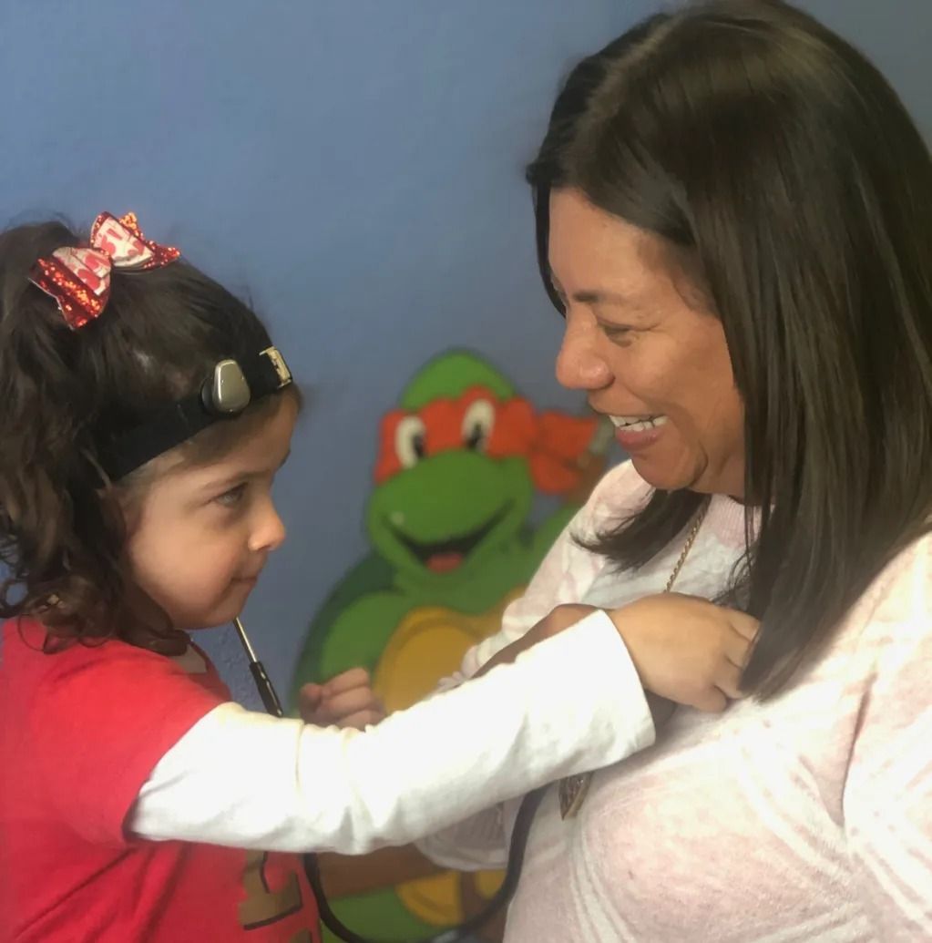 A little girl is listening to a woman 's heartbeat with a stethoscope