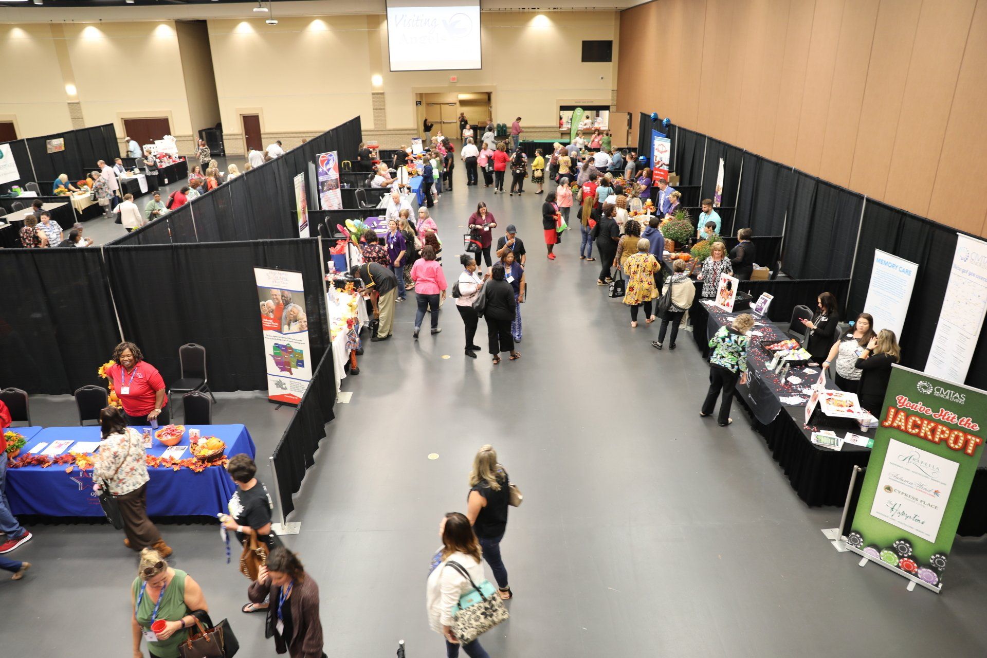 A large room filled with people standing around tables.