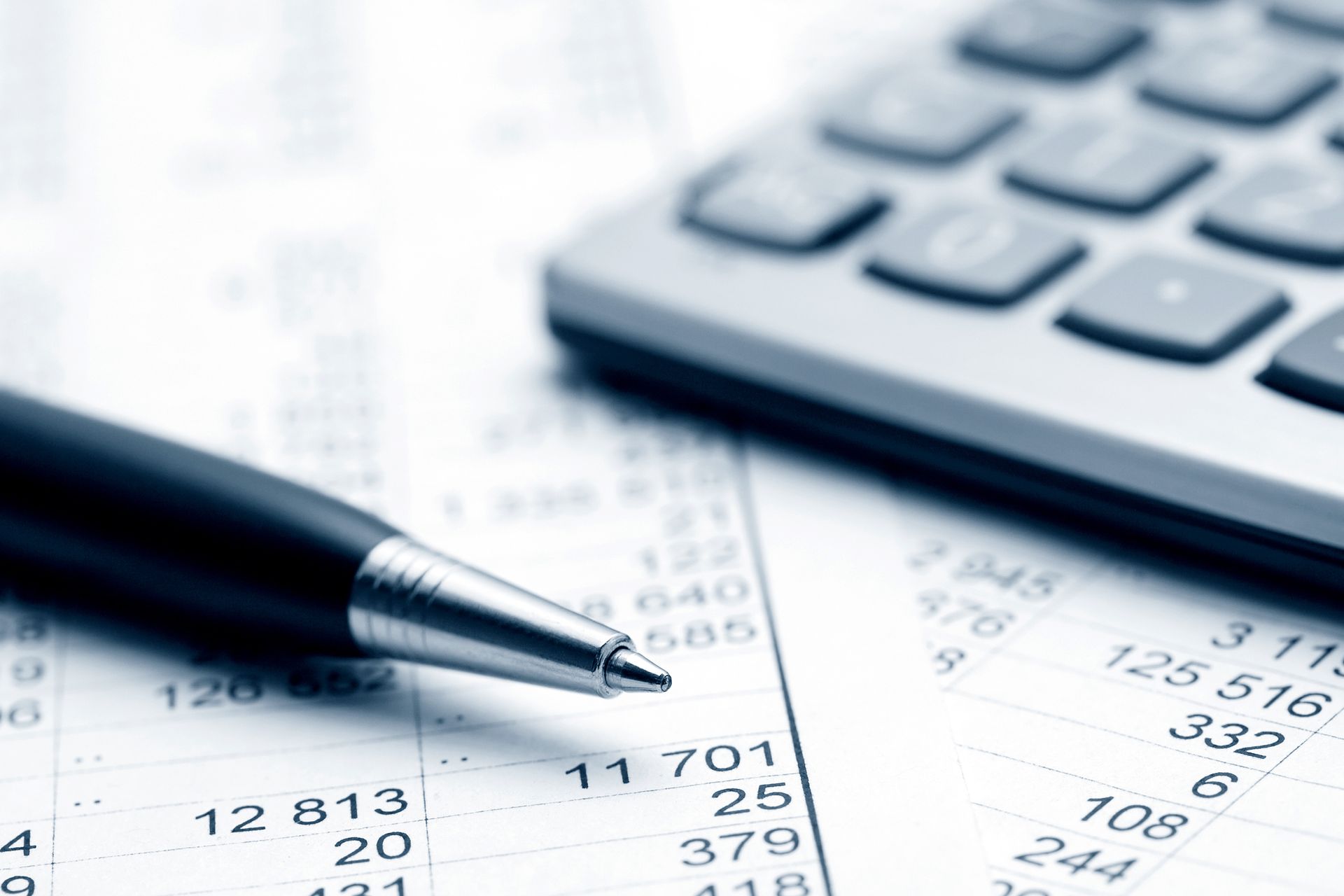 Close-up of a pen, calculator, and financial documents with numbers.