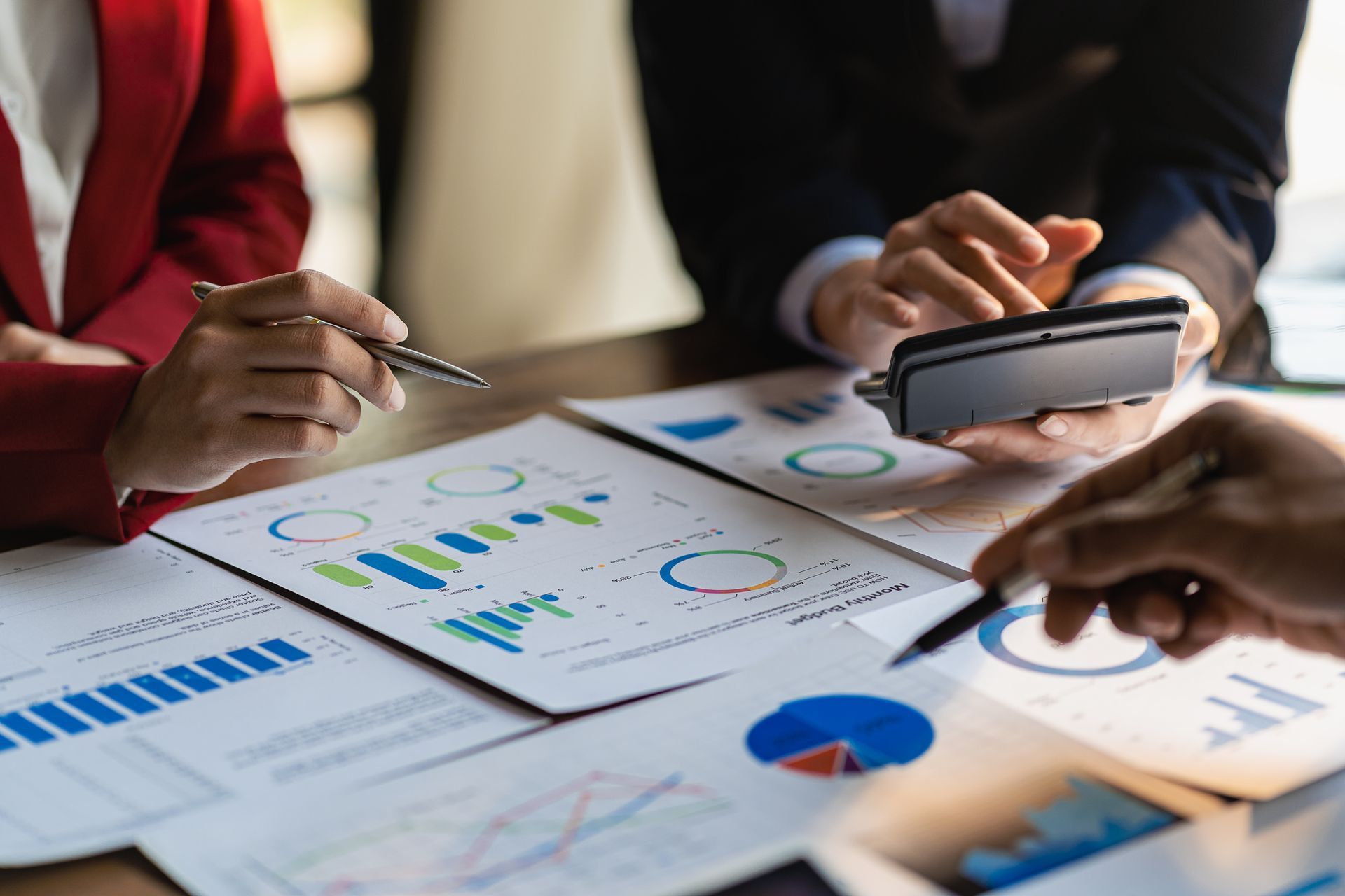 People reviewing financial charts and using a calculator at a table.