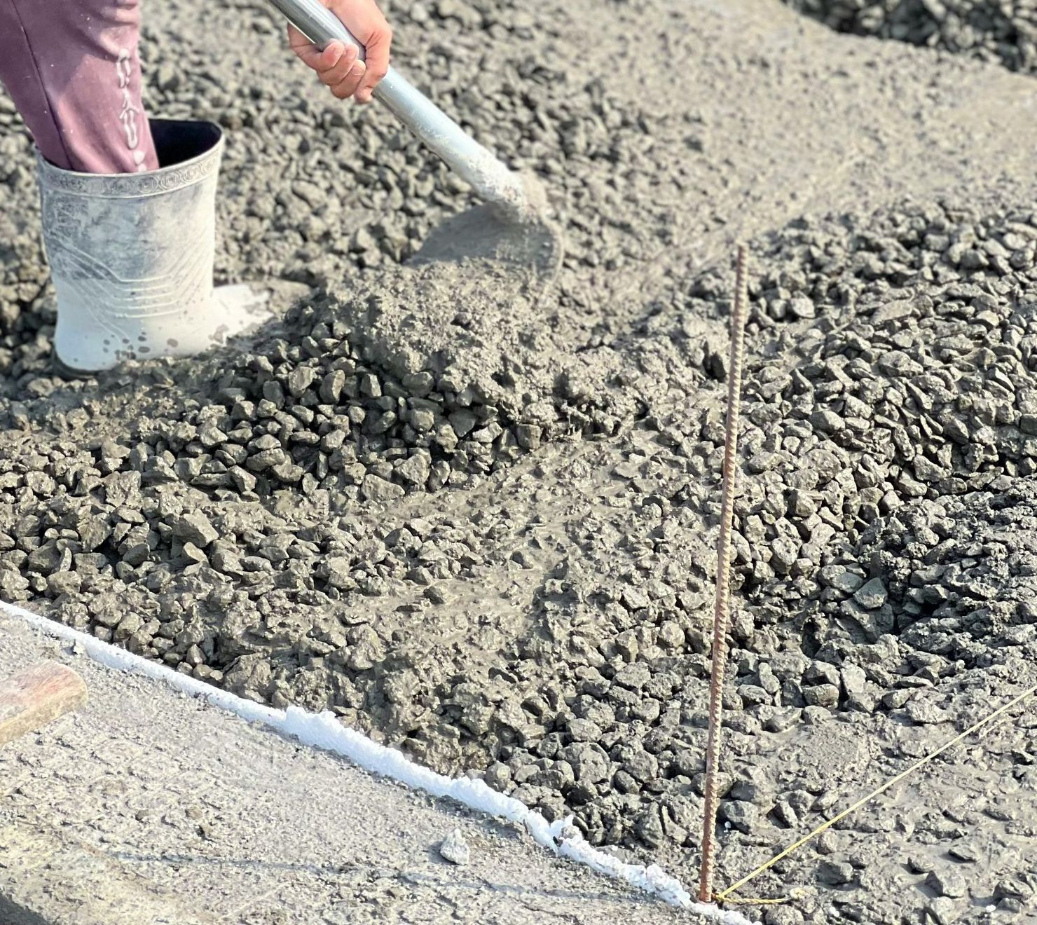 A person is pouring concrete with a shovel.
