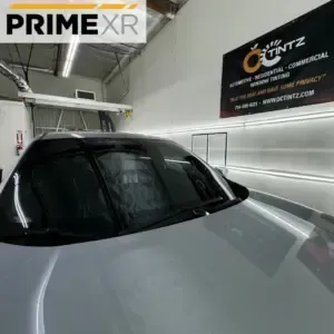 Car with tinted windows in shop. Sign for OC Tintz visible.