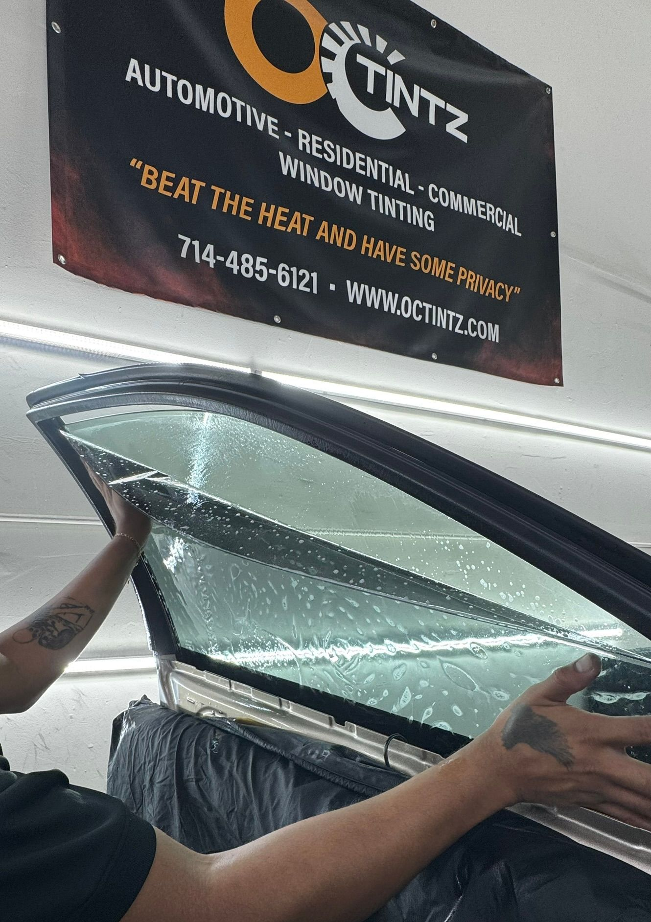 Person applying window tint film to a car window.