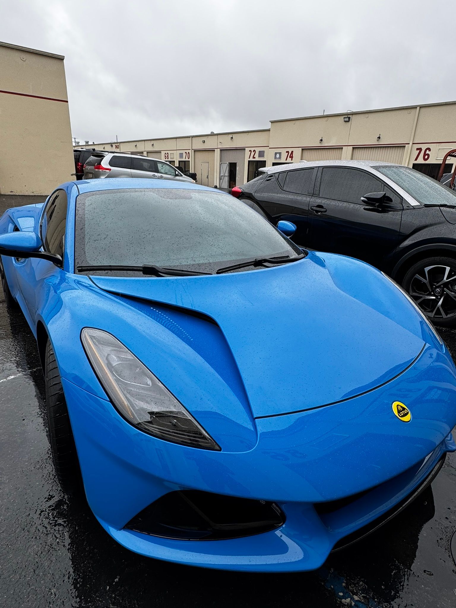 Bright blue sports car parked on wet pavement.