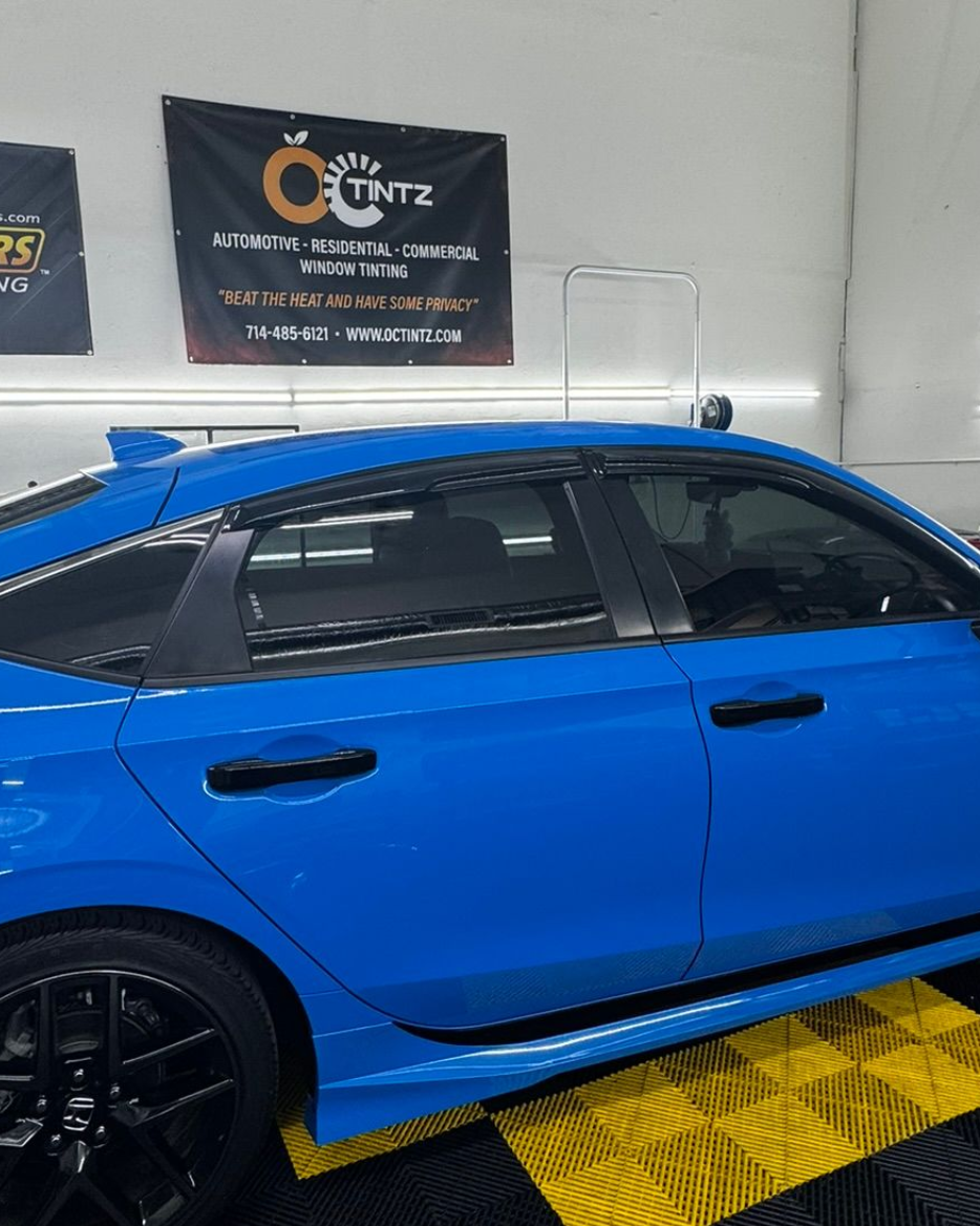 Person installing window tint on a car window, holding the film in place.